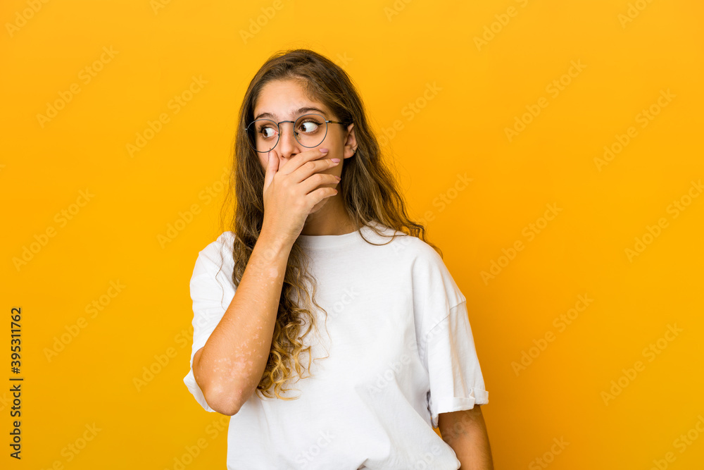 Young caucasian woman thoughtful looking to a copy space covering mouth with hand. Young caucasian woman thoughtful looking to a copy space covering mouth with hand.