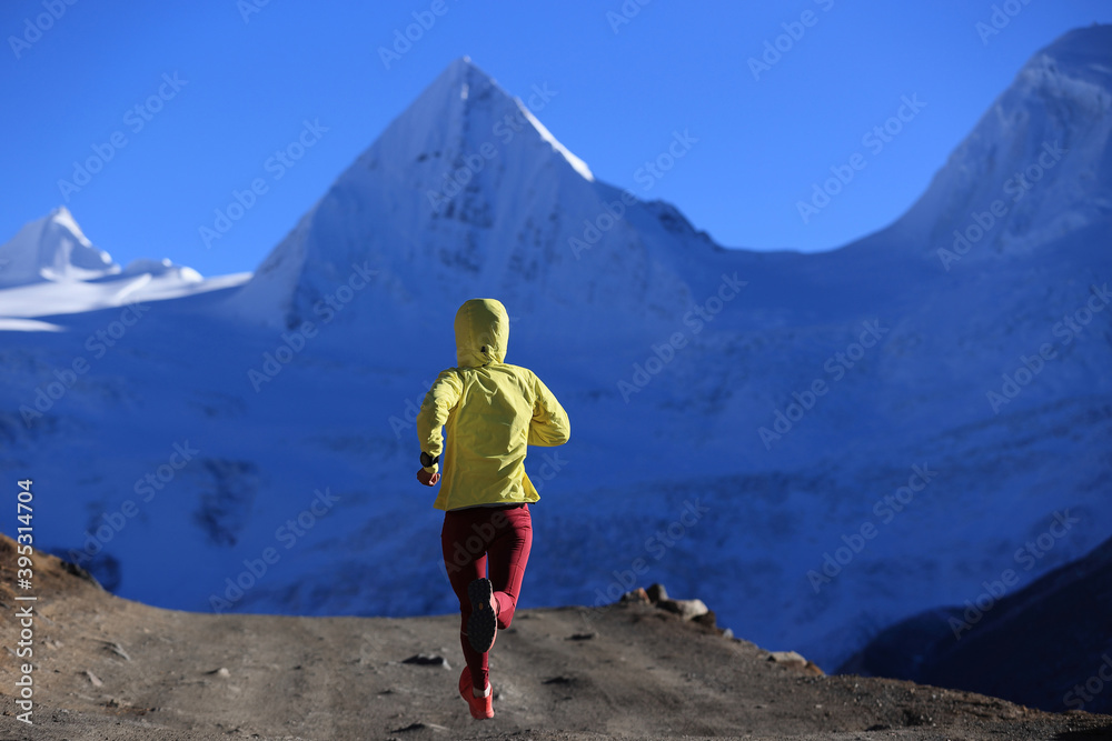 Woman trail runner cross country running  in winter mountains