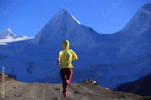 Woman trail runner cross country running in winter mountains