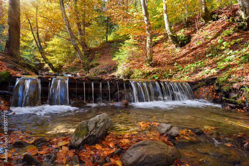 Fototapeta Naklejka Na Ścianę i Meble -  Beautiful landscape with a waterfall in the autumn forest. Autumn sunny day