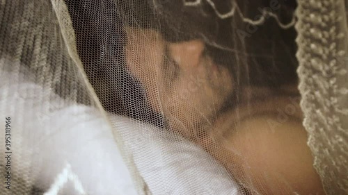 man lies under mosquito net at night