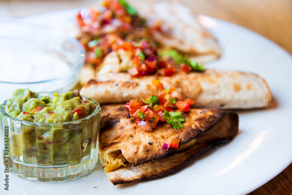 Delicious Mexican quesallidas made with chicken, tomato pieces and served with guacamole sauce.