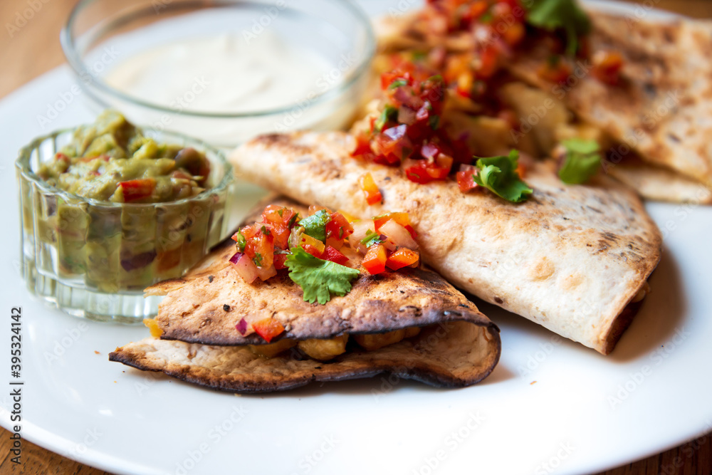 Delicious Mexican quesallidas made with chicken, tomato pieces and served with guacamole sauce. Delicious Mexican quesallidas made with chicken, tomato pieces and served with guacamole sauce.