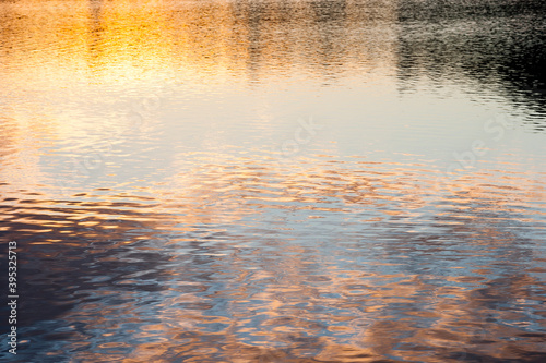 Golden sunlight and blue sky reflecting off gently rippling water.