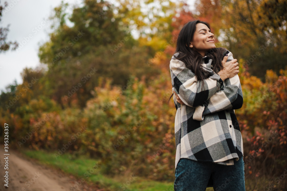Beautiful happy woman smiling while strolling in autumn forest Beautiful happy woman smiling while strolling in autumn forest