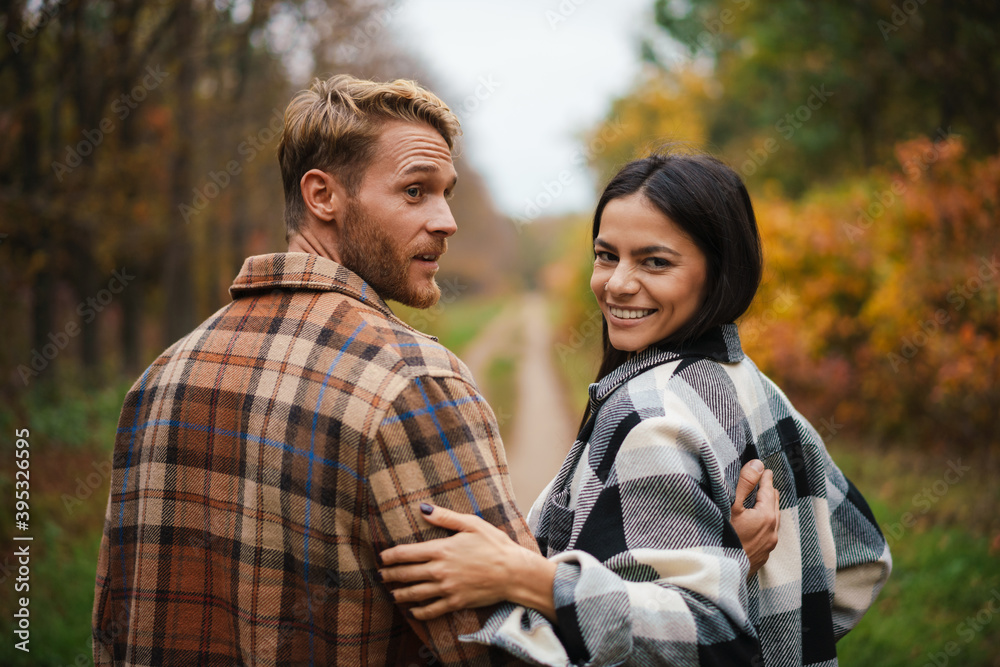 Beautiful happy couple smiling and hugging while strolling in forest Beautiful happy couple smiling and hugging while strolling in forest