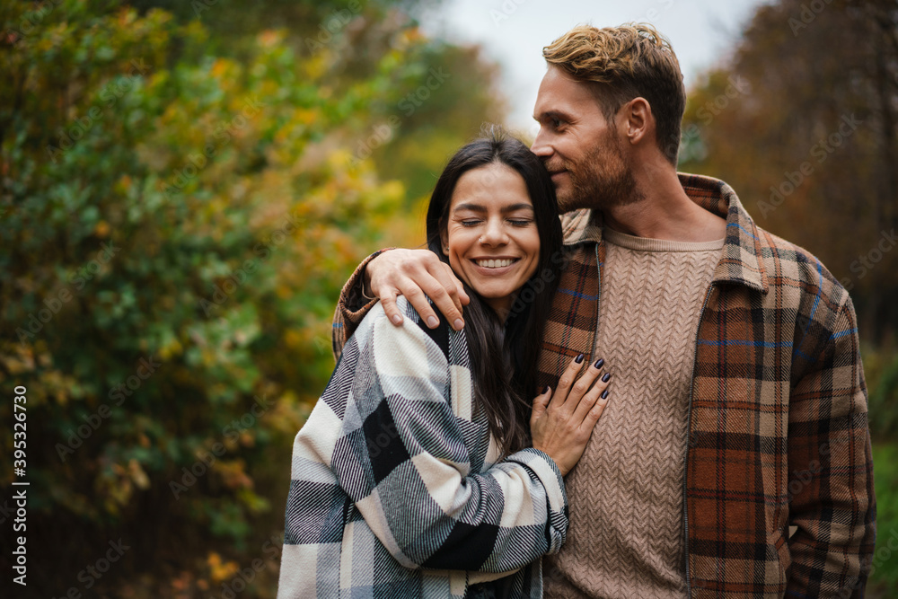 Beautiful happy couple smiling and hugging while strolling in forest Beautiful happy couple smiling and hugging while strolling in forest