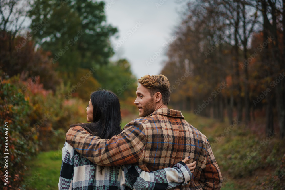 Beautiful happy couple smiling and hugging while strolling in forest Beautiful happy couple smiling and hugging while strolling in forest