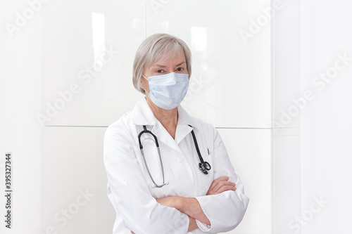 Senior female doctor with protective face mask, white background, copy or text space.