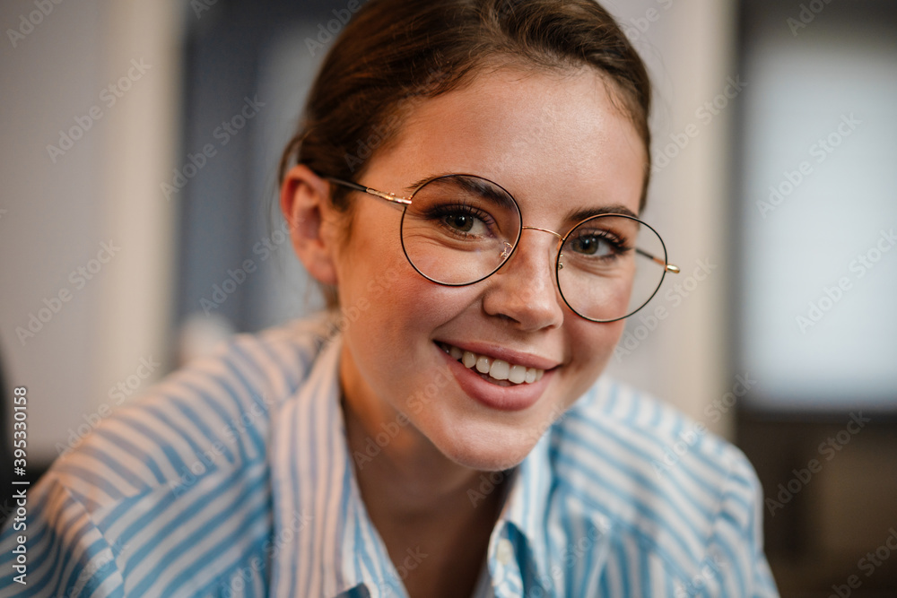 Beautiful happy girl in eyeglasses smiling and looking at camera Beautiful happy girl in eyeglasses smiling and looking at camera