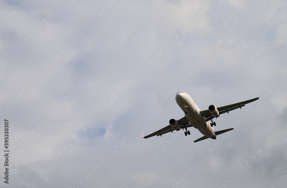 Closeup of an airplane flying on the sky with cloudy sky background. 