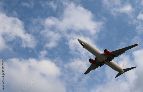 Closeup of an airplane flying on the sky with cloudy blue sky background. 