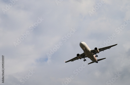Closeup of an airplane flying on the sky with cloudy sky background. 