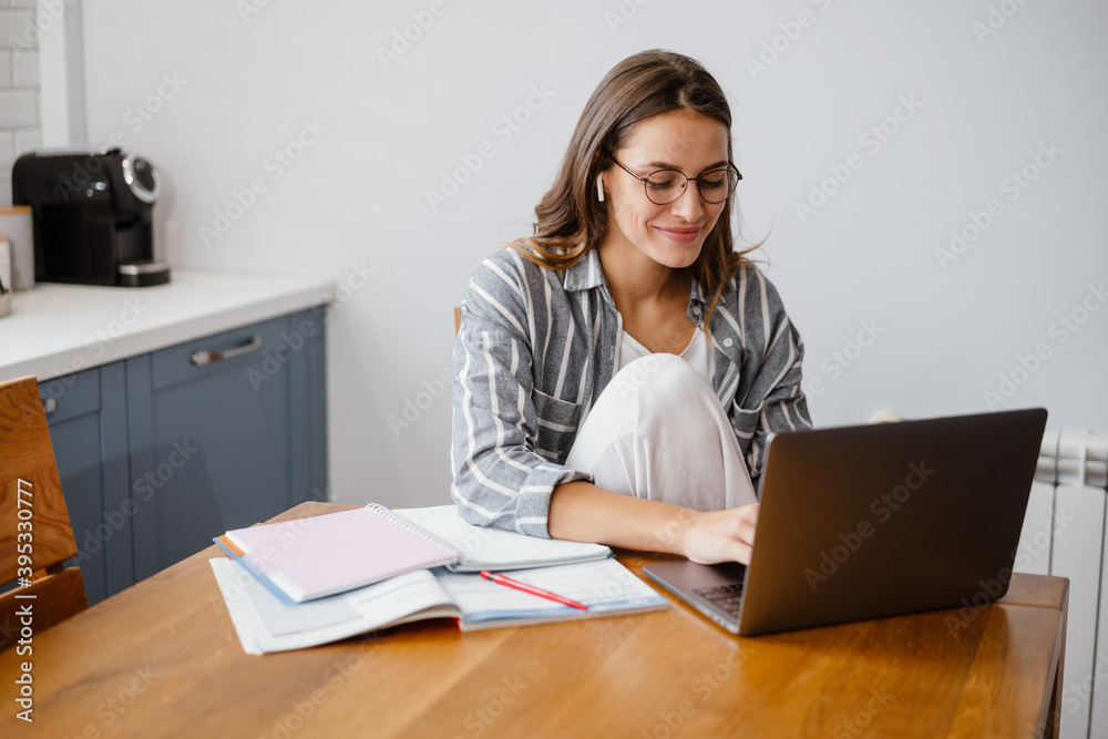Cheerful beautiful woman doing homework with laptop Cheerful beautiful woman doing homework with laptop