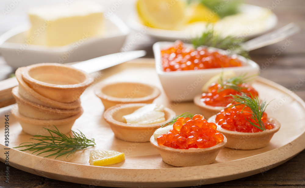 cooking tartlets with red caviar on wooden table