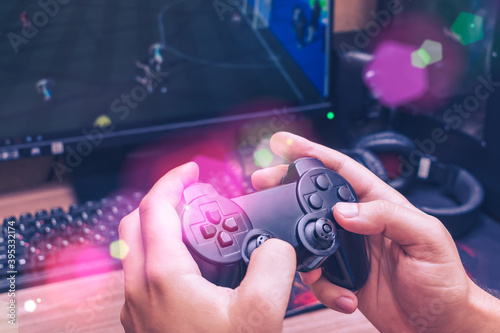 Man holds a game joystick in his hands while playing a video game