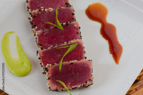 Ahi tuna, pan sesame seared rare. Premium sushi grade tuna seared and served with avocado, cucumber, caviar, ginger, wasabi and soy. Classic fine dining appetizer. photo