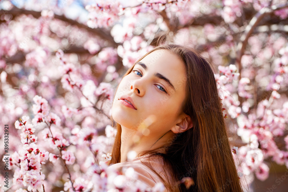 Young girl posing near blossom cherry tree with pink flowers Young girl posing near blossom cherry tree with pink flowers