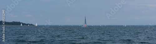 Chiemsee, Germany - August 25, 2019: sailboats on the lake "Chiemsee", in the background the mountains "Alps" - the island "Fraueninsel"
