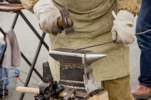 Blacksmith with a hammer on an anvil prepares a detail photo