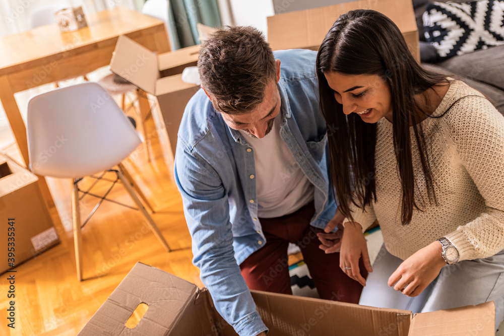 Smiling young couple move into a new home sitting on floor and unpacking. Smiling young couple move into a new home sitting on floor and unpacking.
