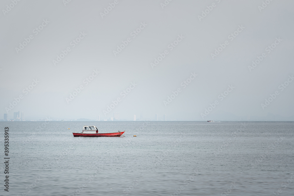 A local wooden fishing boat is floating on the ocean with misty  environment in the morning.