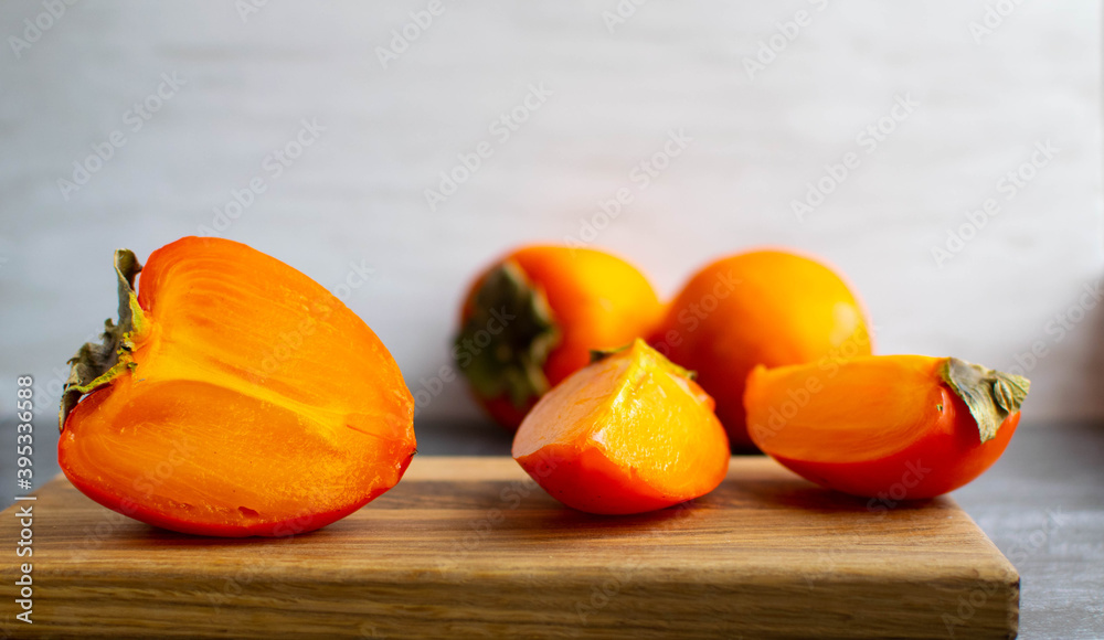 Ripe orange persimmon sliced on a Board on a light background. A healthy snack option.