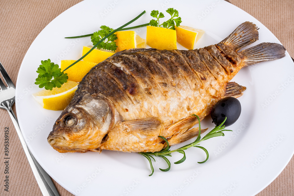 Fried fish on white plate with fork and knife Fried fish on white plate with fork and knife