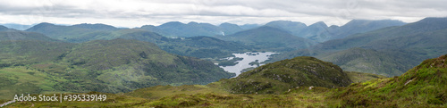 Panoramic view of the Irish countryside with trees, green vegetation and lakes with mountains and hills, cloudy day in Ireland