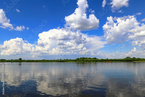 White cumulus clouds are reflected in the Neman river