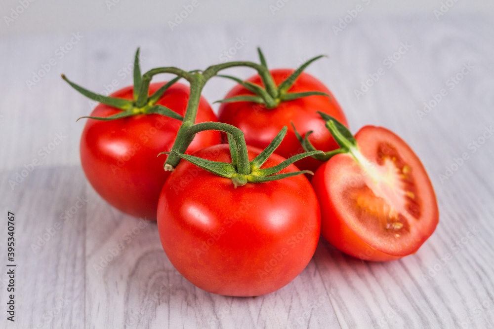 Raw and fresh-cut tomatoes on a white wooden table. Luminous background. Raw and fresh-cut tomatoes on a white wooden table. Luminous background.