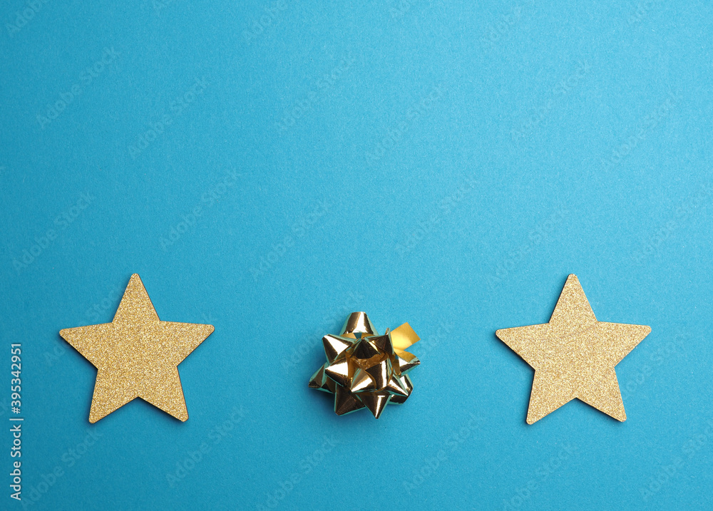 Christmas background with golden stars and bow on blue with space for text Christmas background with golden stars and bow on blue with space for text