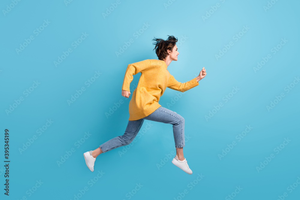Full length body side profile photo of happy girl running fast jumping high isolated on bright blue color background