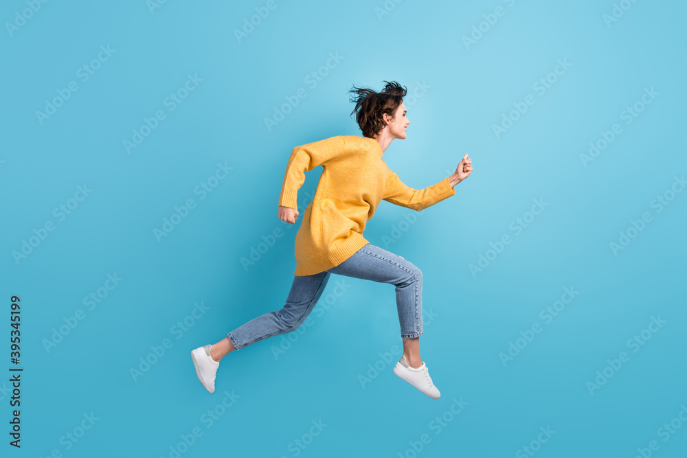 Full length body side profile photo of happy girl running fast jumping high isolated on bright blue color background Full length body side profile photo of happy girl running fast jumping high isolated on bright blue color background