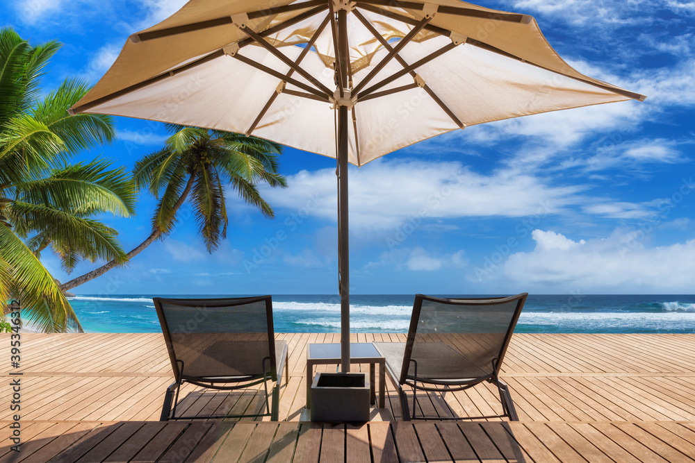 Sunny beach with umbrella and deckchairs on wooden floor, palm trees and the turquoise sea on Tropical island. Sunny beach with umbrella and deckchairs on wooden floor, palm trees and the turquoise sea on Tropical island.