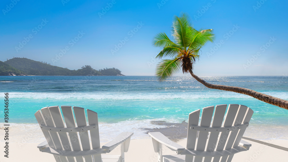 Sunny beach with beach chairs on white sand, tropical sea and coco palms. Summer vacation and tropical beach concept.	