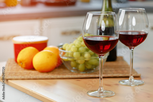 Two wine glasses with red wine on wooden kitchen counter