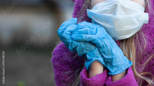 Close up medical mask and blue  latex protective gloves on a teen blond girl in purple hoodie. New normal. Protection and prevention covid 19. Selective focus. © Natallia