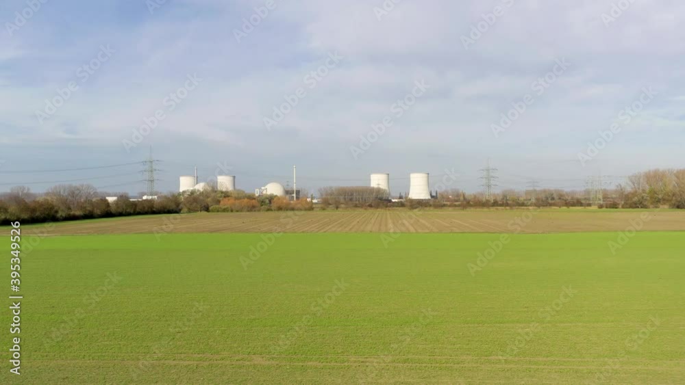 Drone video of an ascending flight towards a nuclear power plant over an agricultural field during the day Drone video of an ascending flight towards a nuclear power plant over an agricultural field during the day