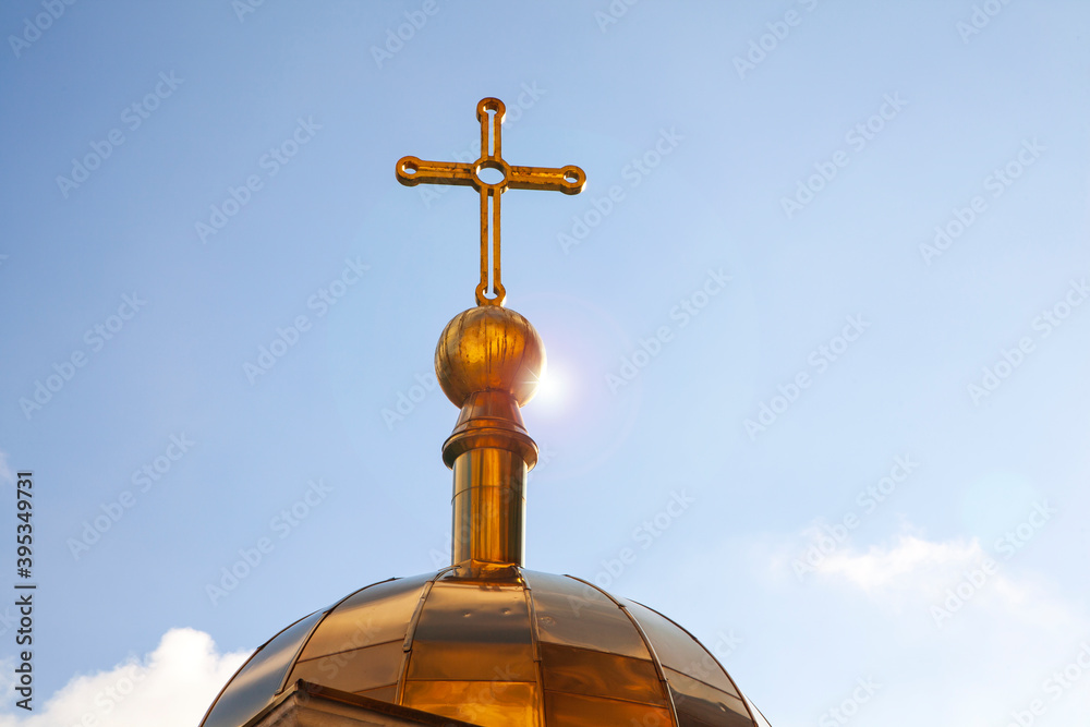 Christian cross on the golden dome of the church, close-up against the blue sky. Christian cross on the golden dome of the church, close-up against the blue sky.