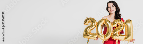  woman holding festive balloons in shape of 2021 numbers isolated on grey, banner photo