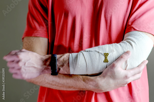 The man supports the injured hand. Primary care, the hand is tightly fixed with an elastic bandage.