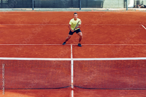 Young handsome man playing tennis on the tennis court © fotofabrika