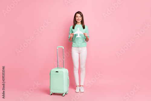 Full length body size view of pretty cheery girl traveler holding in hand paper plane safe arrival isolated on pink color background
