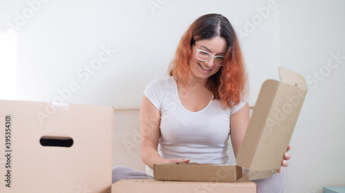 Caucasian woman opens an order while sitting in bed. Online shopping concept with home delivery © Михаил Решетников