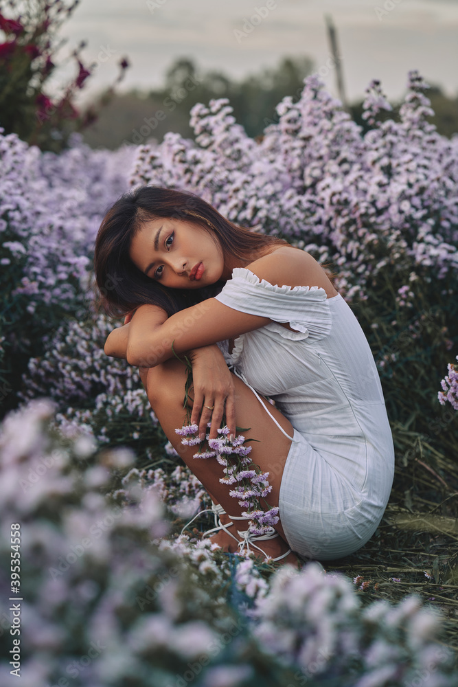 stylish young asian woman wearing white dress posing at the purple flowers field