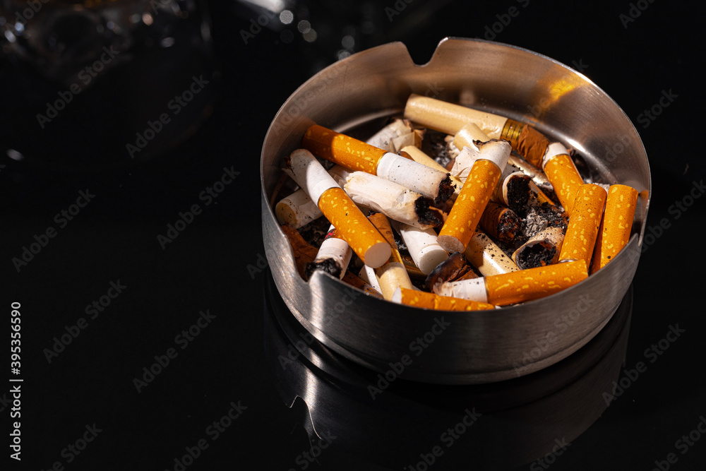 Ash tray full of cigarette butts on black background Ash tray full of cigarette butts on black background
