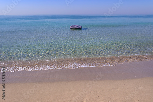 Summertime. The most beautiful sandy beaches of Apulia: inflatable mattress on crystal clear sea in Salento, Italy.
