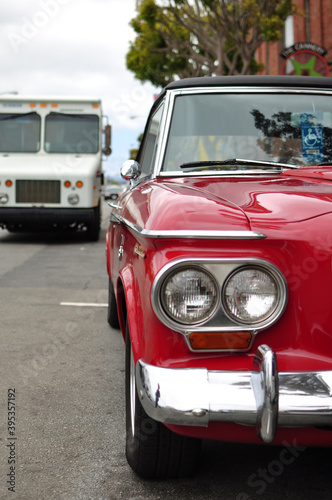 Close up of the front of a red vintage car parked on the street