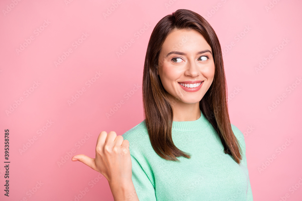 Photo of charming girl direct thumb look empty space shiny smile wear teal sweater isolated pink color background Photo of charming girl direct thumb look empty space shiny smile wear teal sweater isolated pink color background